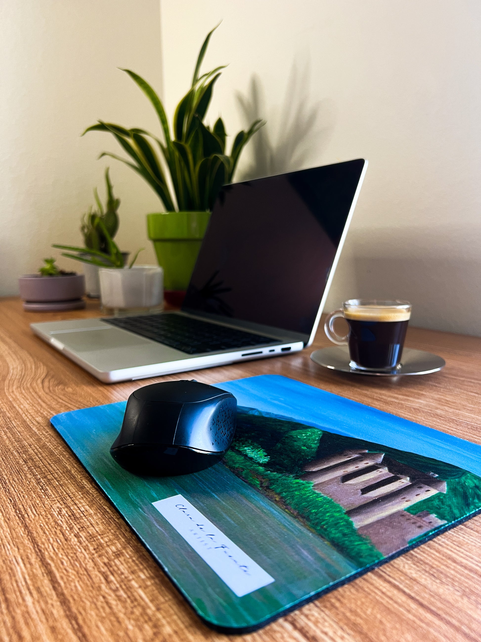 Scotland mousepad inspired in Scottish Eilean Donan castle in a home office setting with a laptop, coffee and plants